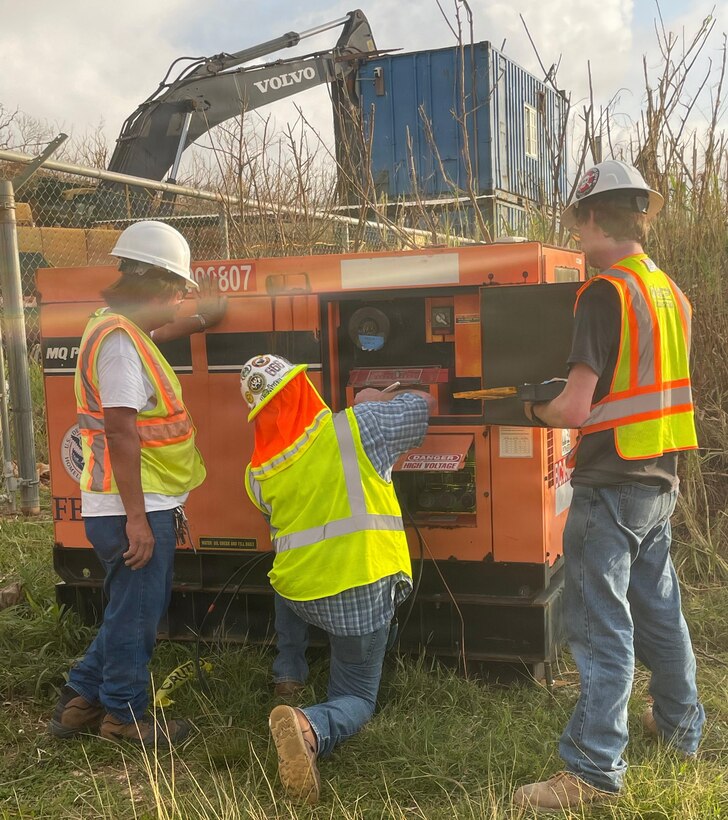 Three men work on a generator
