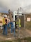 A soldier and another man look at water pipes.