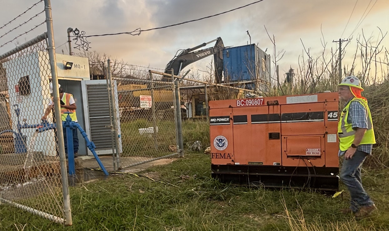 Men open a valve to have water flow from a pump that is connected to a generator.