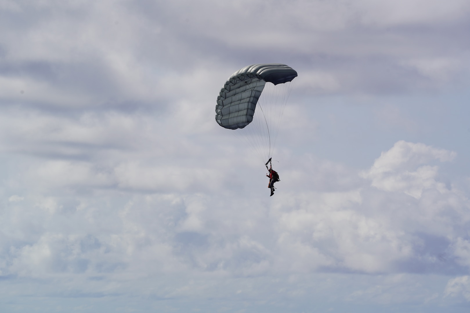 A parajumper assigned to the U.S. Air Force 31st Rescue Squadron floats down after deploying from an Air Force 36th Airlift Squadron C-130 Hercules airplane northeast of Pagan in the Commonwealth of the Northern Mariana Islands April 19, 2026. Parajumpers met up with the crew of fast response cutter USCGC Frederick Hatch (WPC 1143) and searched the interior of the capsized cargo vessel Mariana, which initially experienced a disabled engine about 125 nautical miles northwest of Saipan on April 15. (U.S. Coast Guard photo, courtesy Cutter Frederick Hatch)