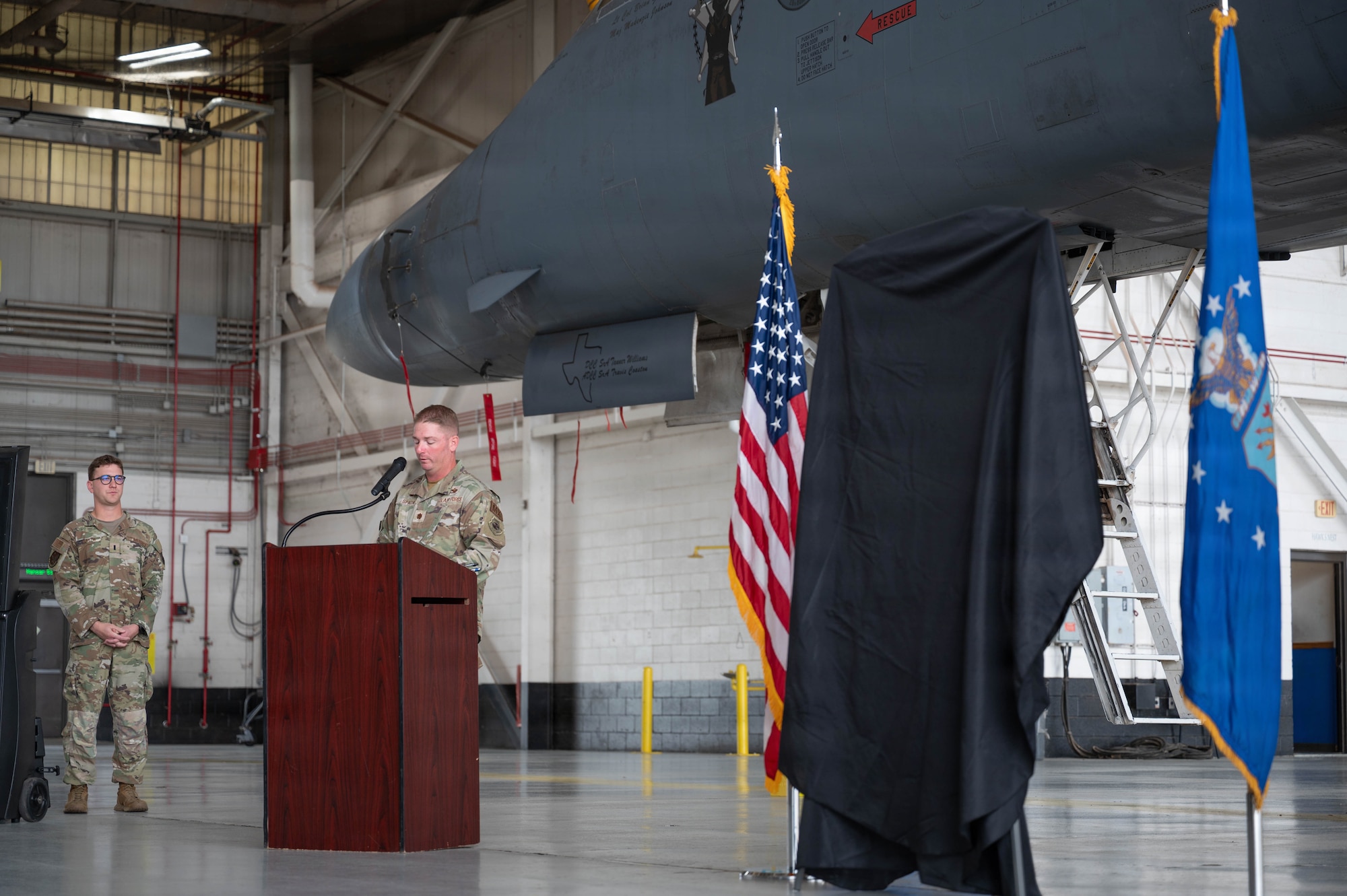Airmen unveil a nose art design inside an airplane hangar
