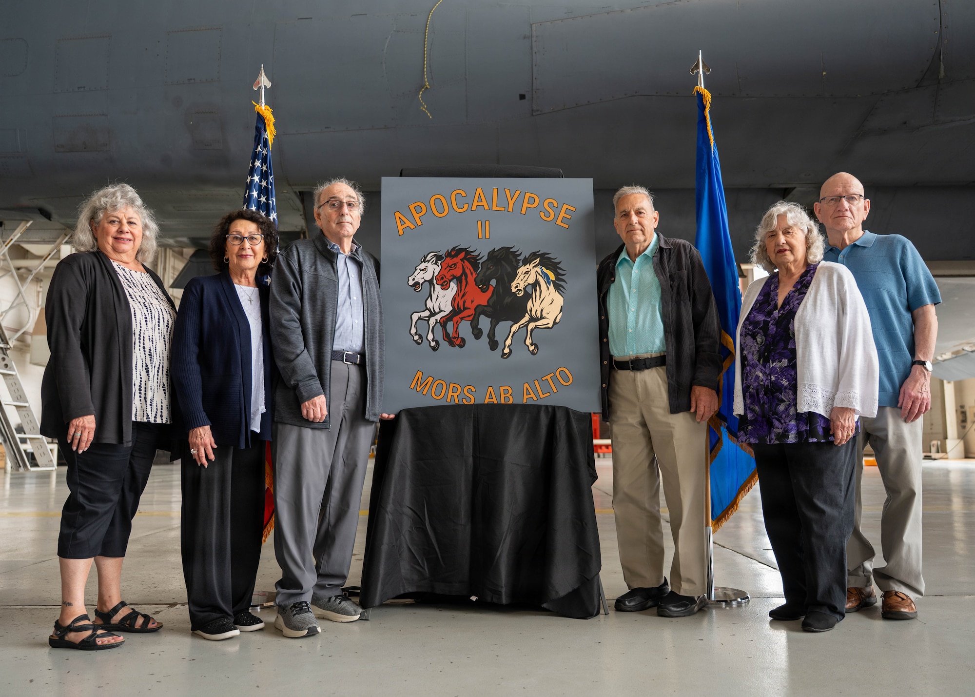Airmen unveil a nose art design inside an airplane hangar