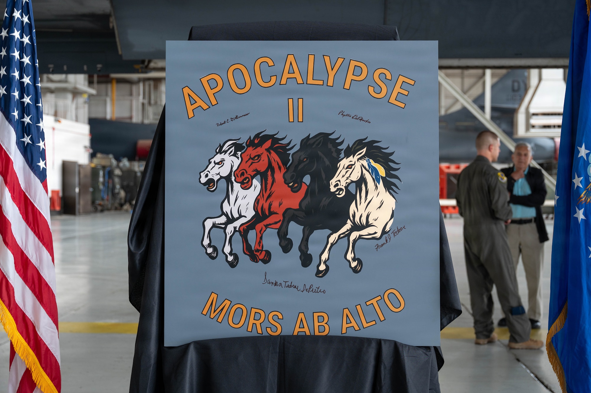 Airmen unveil a nose art design inside an airplane hangar