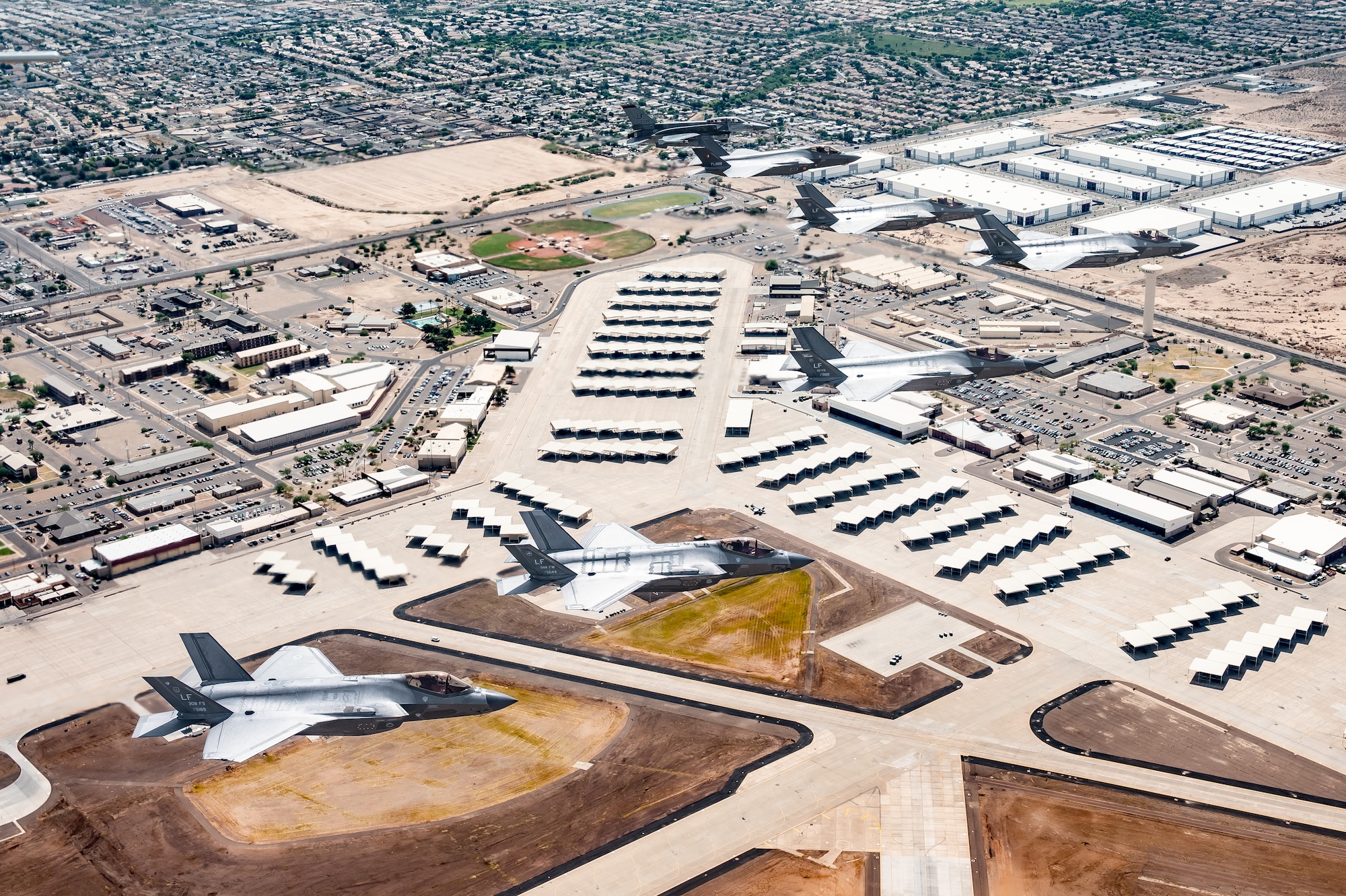 A Republic of Singapore Air Force F-16D Fighting Falcon, a Belgian Air Component F-35A Lightning II, and U.S. Air Force F-35A Lightning II aircraft assigned to the 56th Fighter Wing fly in formation over the base