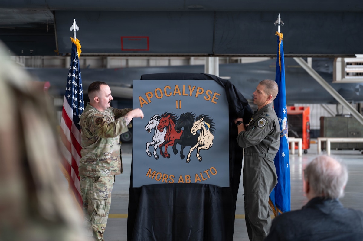 Airmen unveil a nose art design inside an airplane hangar