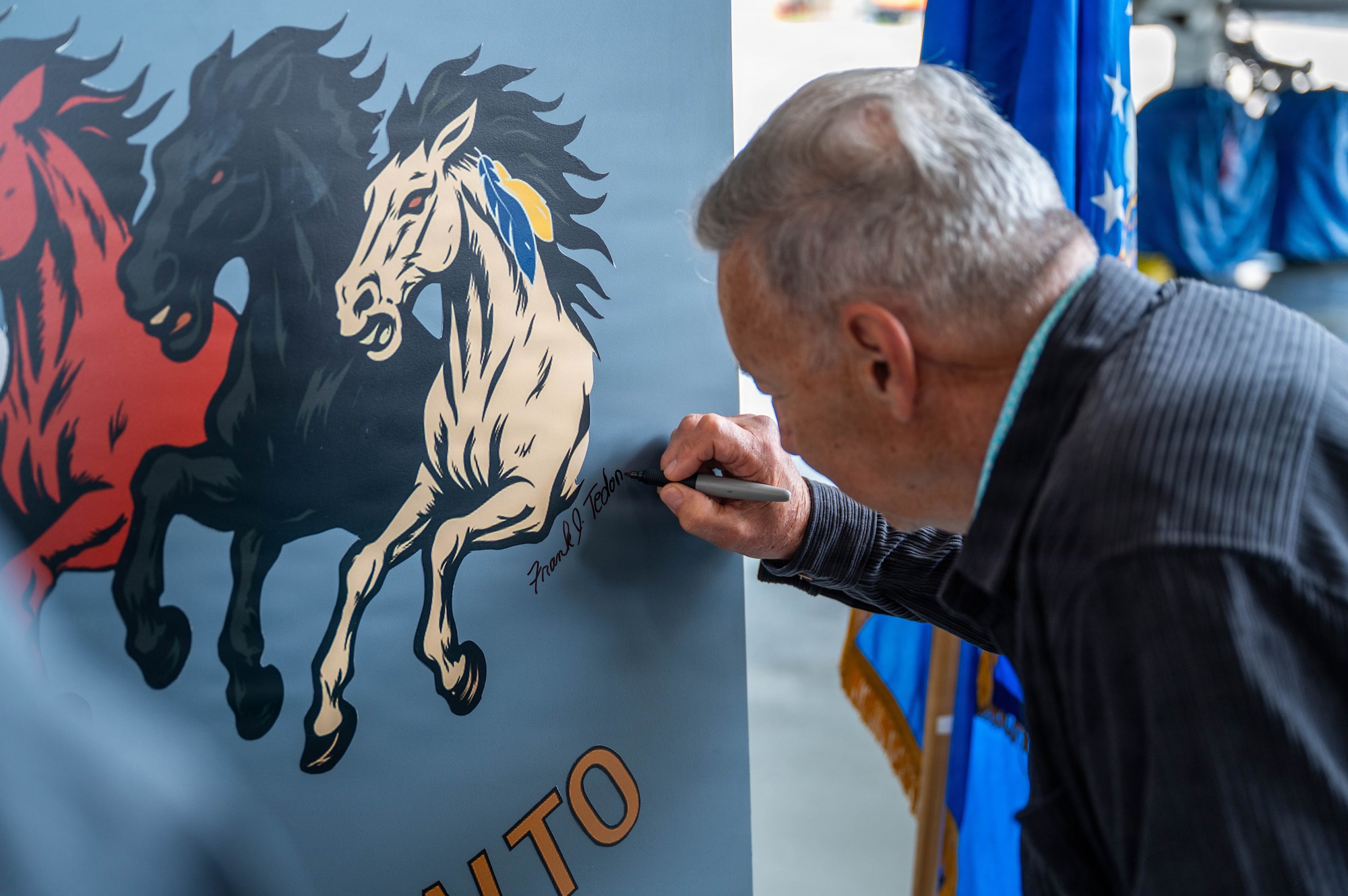 Airmen unveil a nose art design inside an airplane hangar
