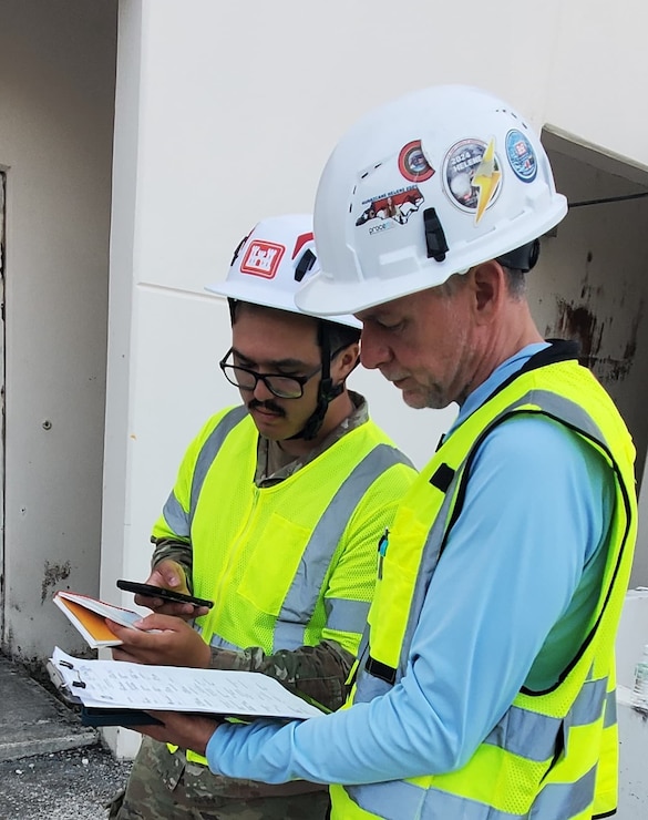 A Soldier and another individual look at a clipboard of information.