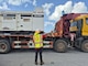 a man directs a truck with large generators loaded on the back.