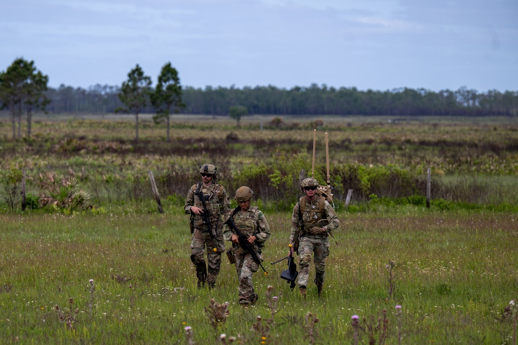 A group of people walk through a field.