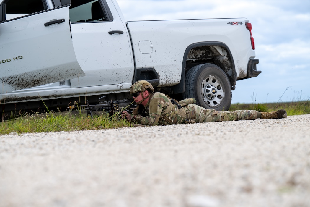 Man lays on the ground with his weapon.