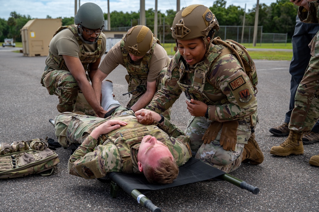 Woman comforts man as he lays on cot.