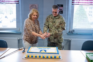 Service member and civilian cut a cake