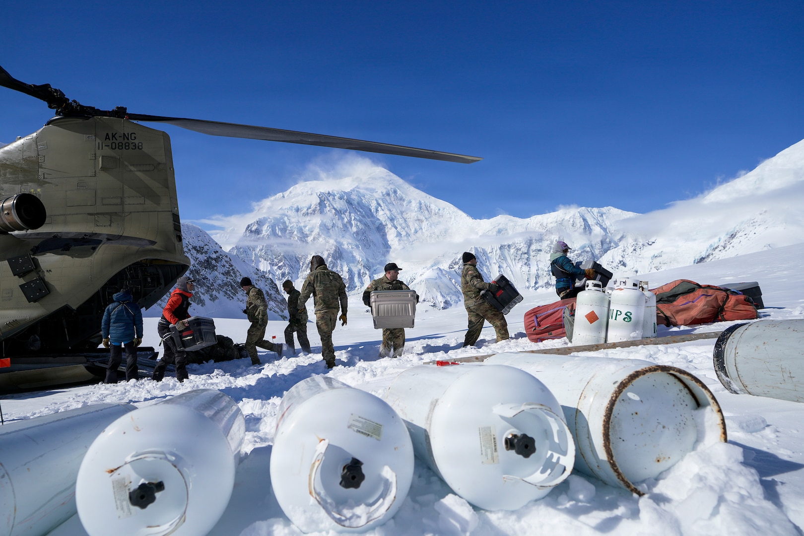 Alaska Army National Guard CH-47F Chinook aircrew members and National Park Service personnel assigned to Denali National Park and Preserve’s Denali Rescue Team offload equipment at Denali Base Camp on the Kahiltna Glacier, April 14, 2026.