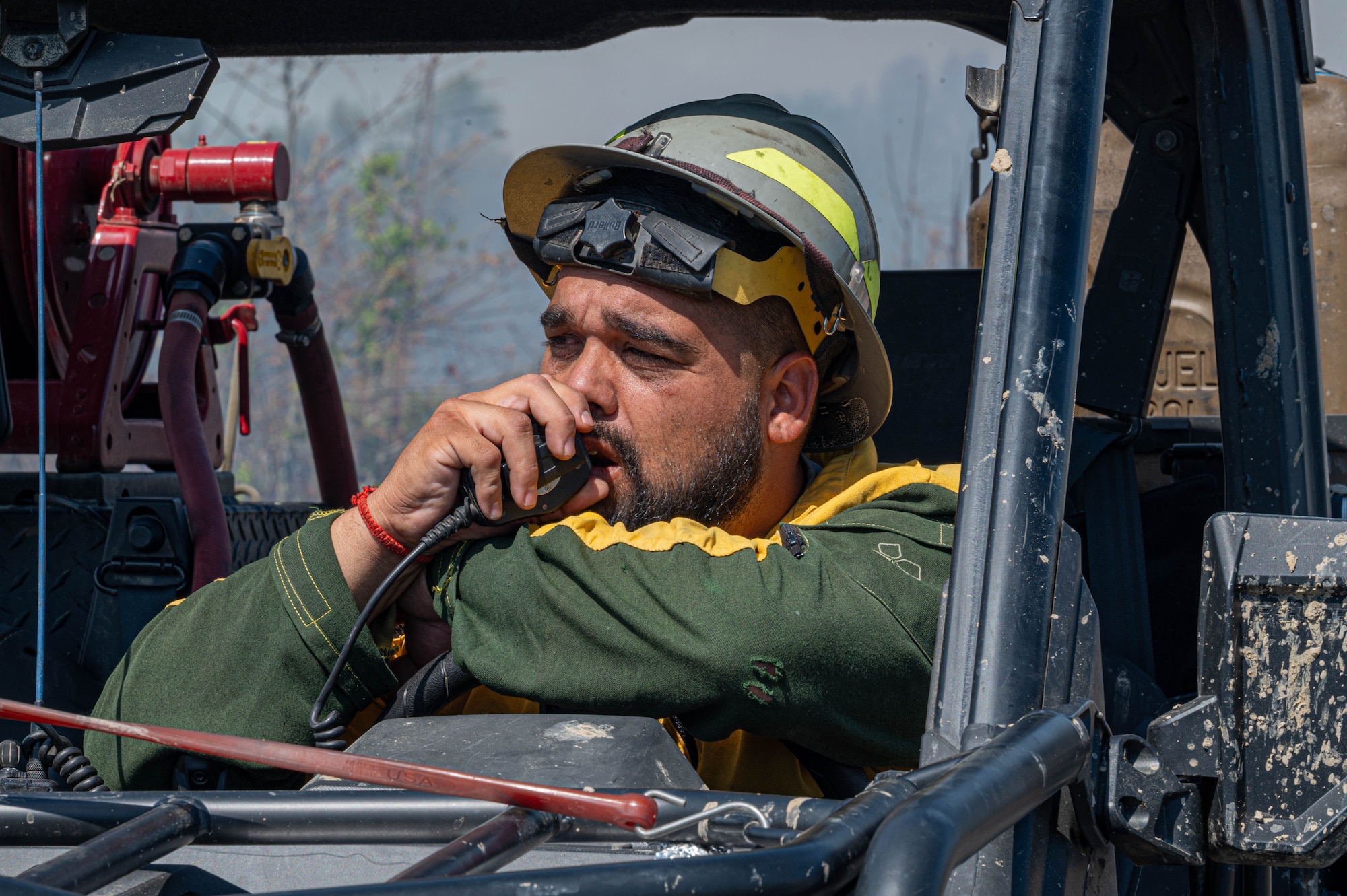 Photos shows a man with a hard hat in an off-road vehicle talking on a radio.