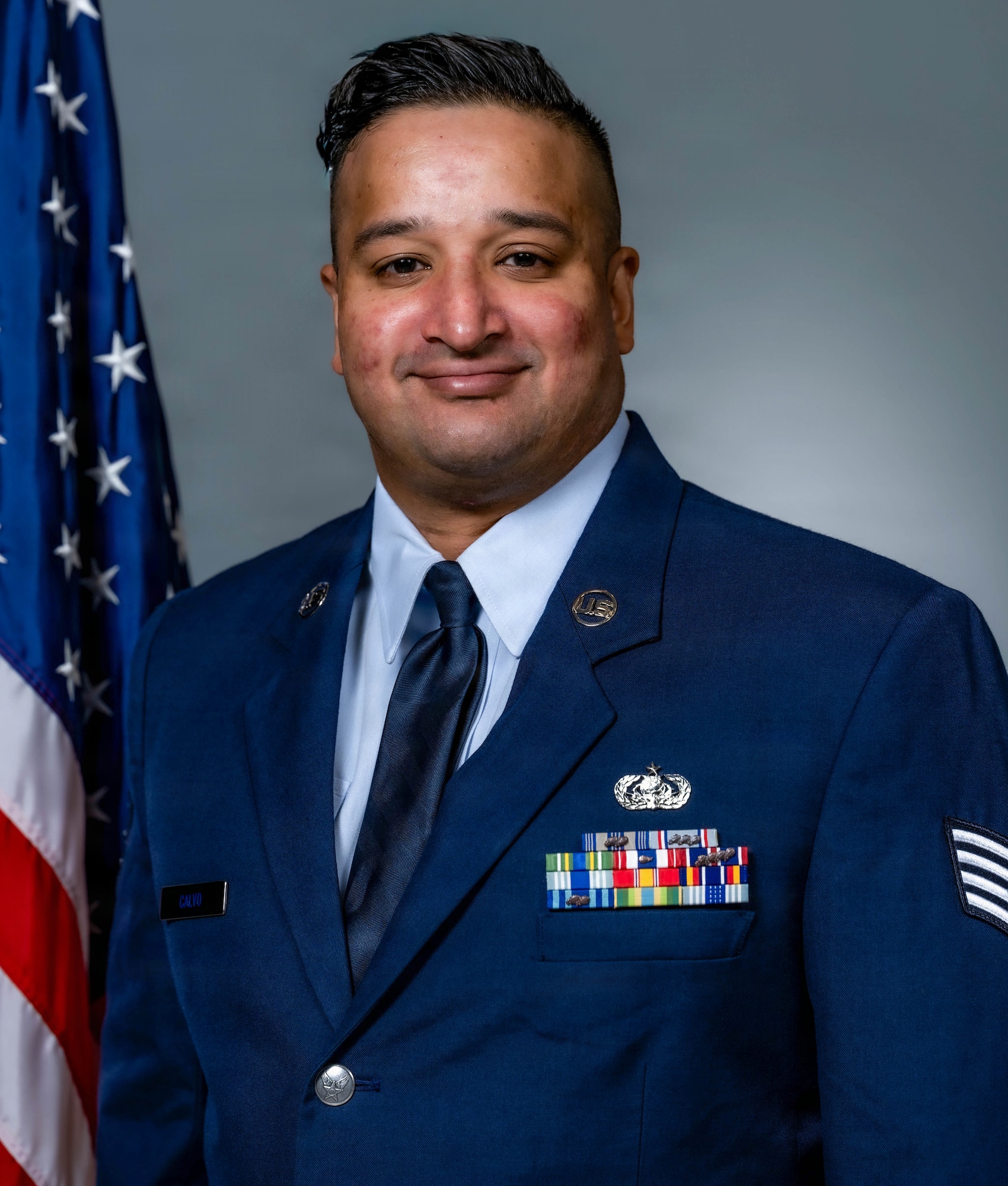 A man in Air Force blues standing in front of an American Flag