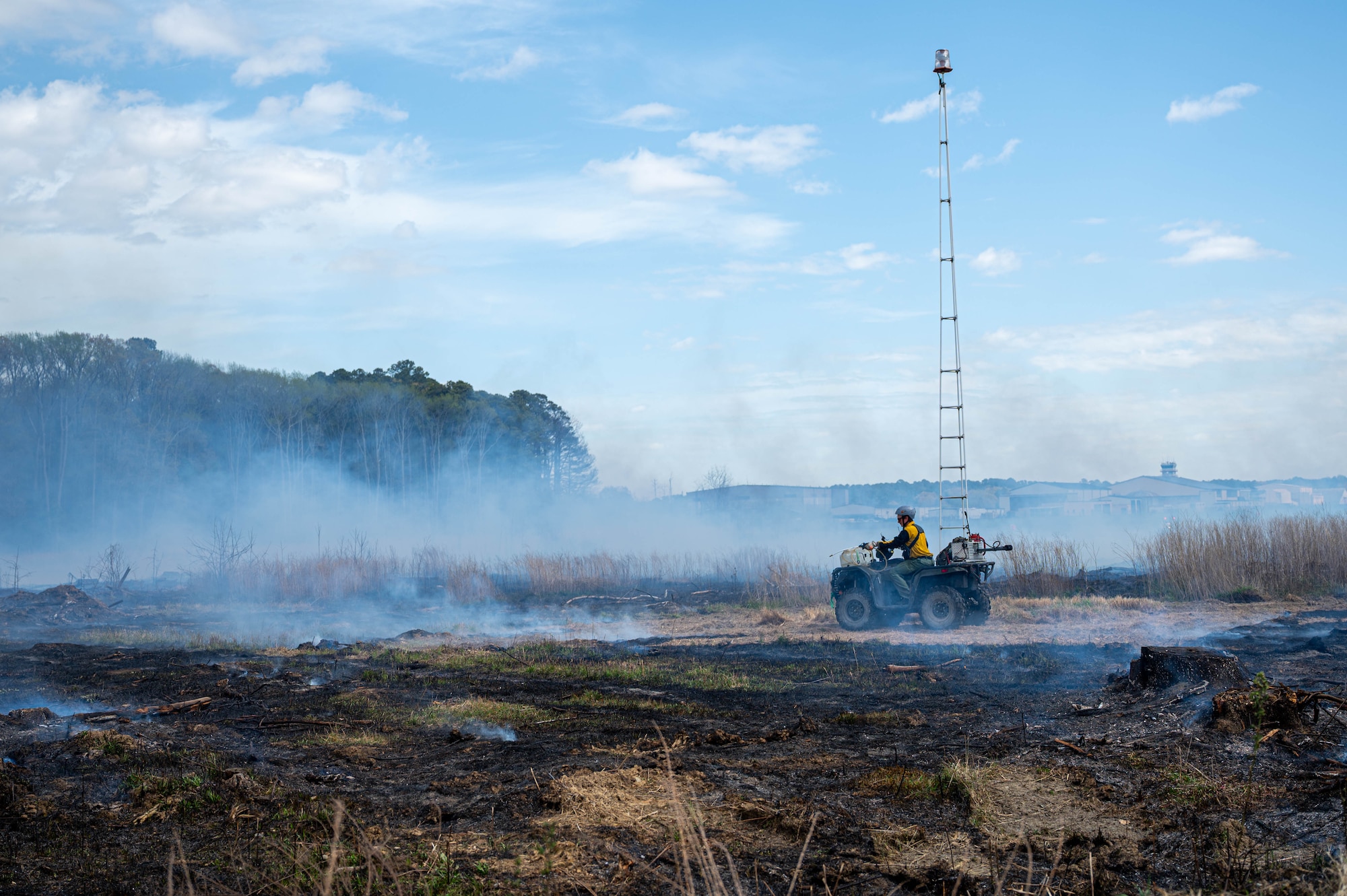 Wide shot photo shows a person on an off-road vehicle using water to clear an area.
