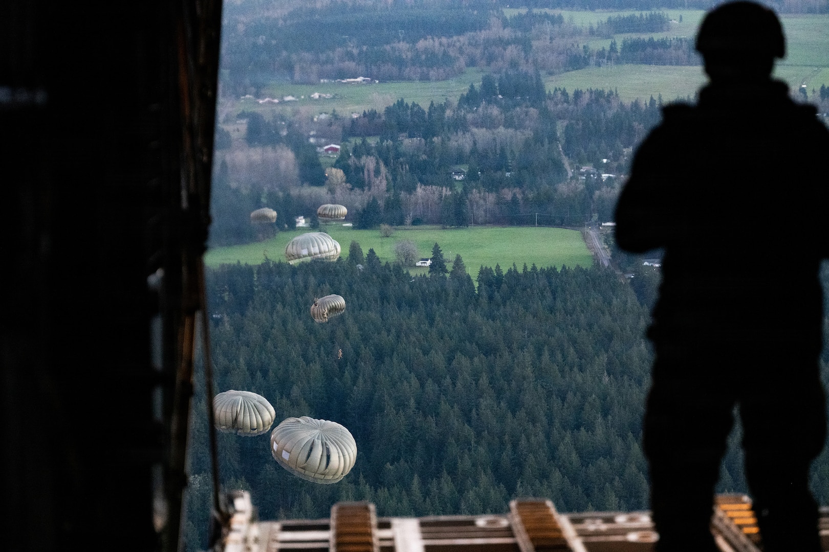 A U.S. Army jumpmaster with the 160th Special Operations Aviation Regiment watches U.S. Army paratroopers after the jump from a C-130 Hercules during Joint Airborne/Air Transportability Training with the Connecticut Air National Guard at Joint Base Lewis-McChord, Wash., March 26, 2026.
