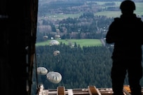 A U.S. Army jumpmaster with the 160th Special Operations Aviation Regiment watches U.S. Army paratroopers after the jump from a C-130 Hercules during Joint Airborne/Air Transportability Training with the Connecticut Air National Guard at Joint Base Lewis-McChord, Wash., March 26, 2026.