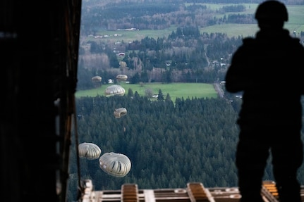 A U.S. Army jumpmaster with the 160th Special Operations Aviation Regiment watches U.S. Army paratroopers after the jump from a C-130 Hercules during Joint Airborne/Air Transportability Training with the Connecticut Air National Guard at Joint Base Lewis-McChord, Wash., March 26, 2026.