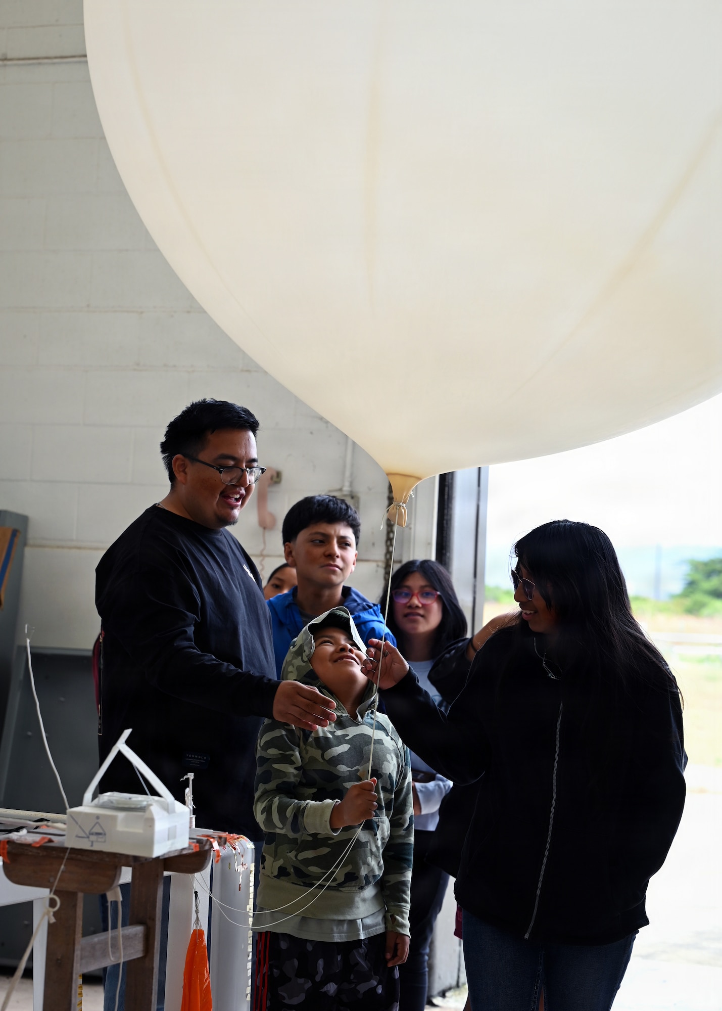 People look at and hold a weather balloon.