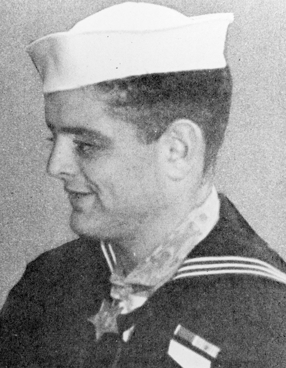 A man in a military dress uniform wearing a ribbon and medal smiles.