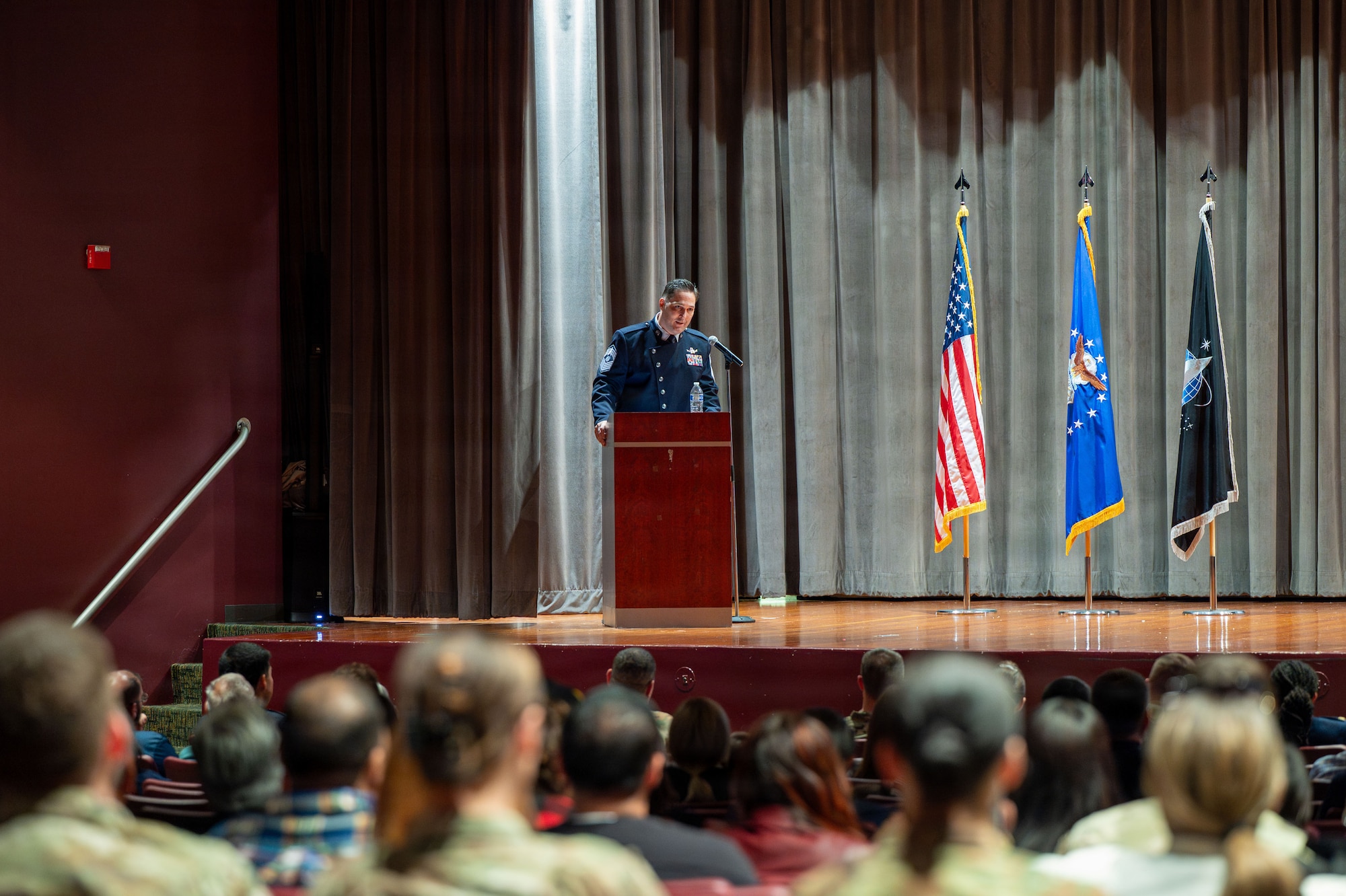 Man stands behind a podium and speaks to a crowd