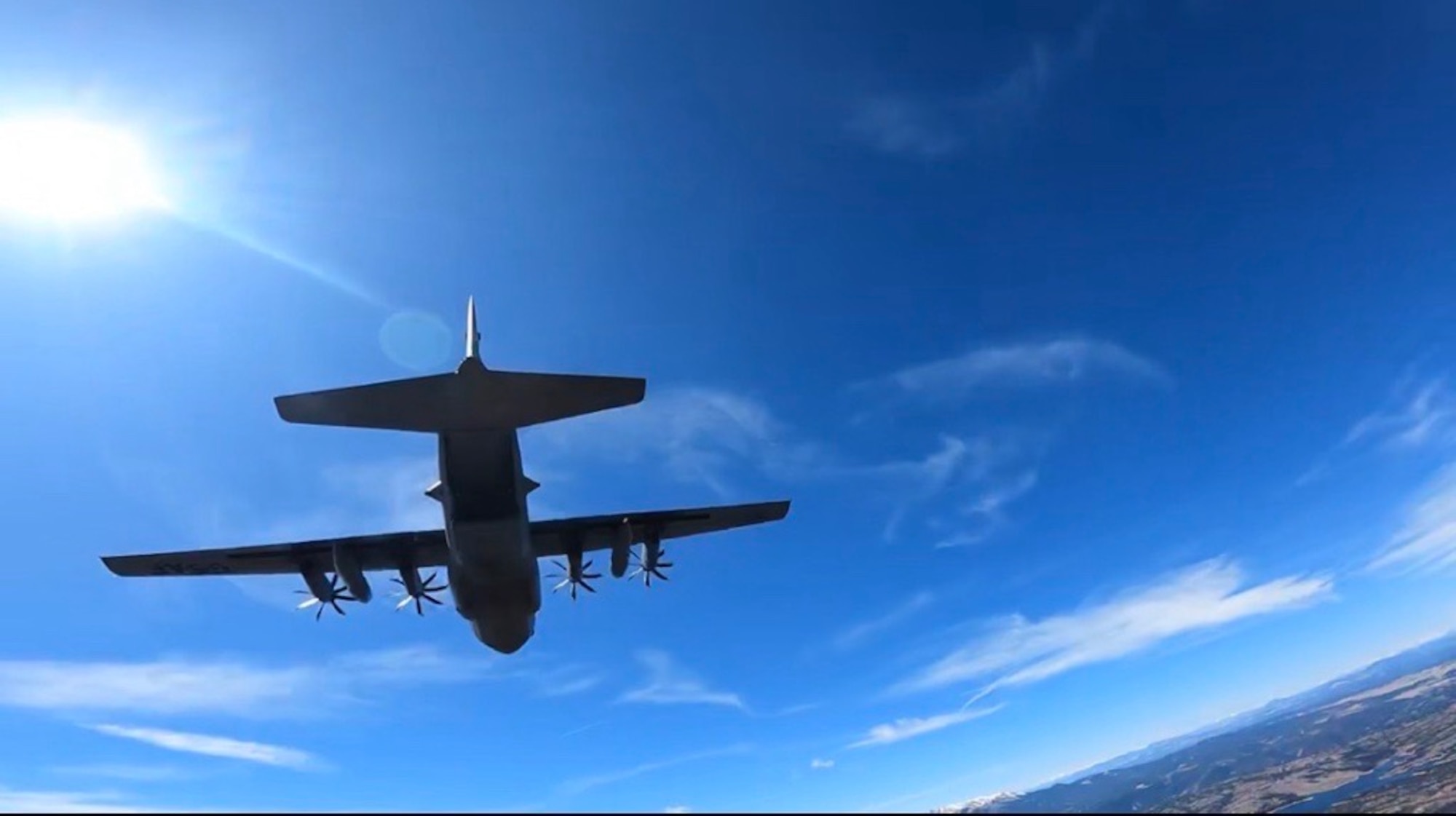 A C-130H Hercules aircraft flies through the sky.