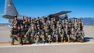A large group of cadets line up on the flight line for a group photo in front of a C-130H Hercules aircraft.