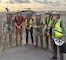 A group of Soldier and civilians wearing flight gear stand in front of a military helicopter.