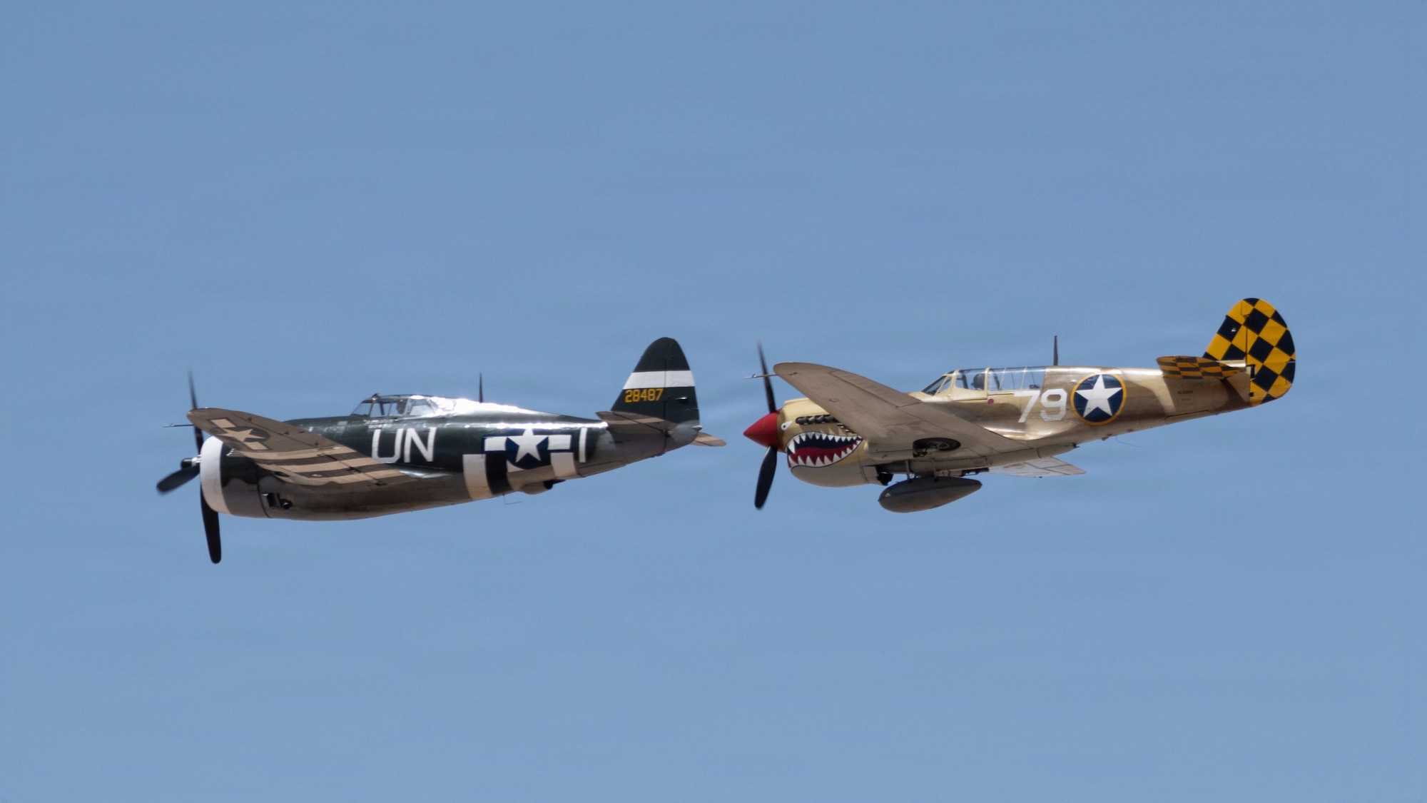 A P47 Thunderbolt, left, and a P-40 Warhawk fly overhead.