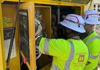 Two soldiers inspect an electrical panel.