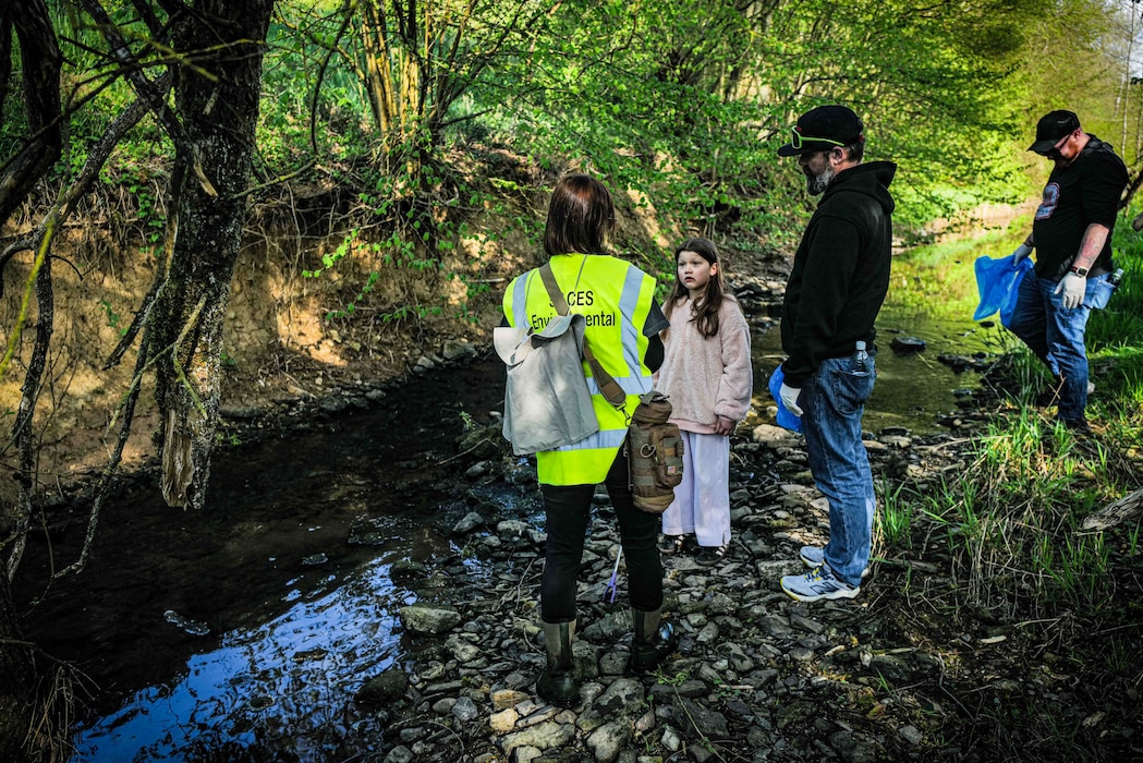 Ashley Riedel, Spangdahlem Air Base tank program manager with the 52nd Civil Engineer Squadron, speaks to a young participant about aquatic wildlife during the annual Spangerbach creek cleanup in Spangdahlem, Germany, April 25, 2026. The 52nd CES environmental office provided participants with leaflets describing the creek's restoration projects along with natural and local historic aspects of the area. (U.S. Air Force photo by Master Sgt. Alexander W. Riedel)
