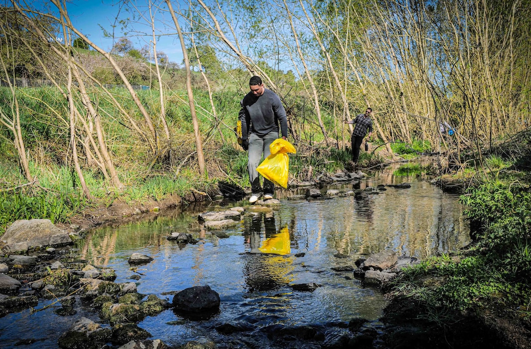 Senior Airman Albert Morel, at front, and Tech. Sgt. Benjamin Sisson, both assigned to 52nd Fighter Wing Staff Agencies, search for debris in the Spangerbach creekbed during the annual creek cleanup in Spangdahlem, Germany, April 25, 2026. Volunteers climbed into the creek's ravines and streambed to remove trash and discarded materials from the waterway. (U.S. Air Force photo by Master Sgt. Alexander W. Riedel)