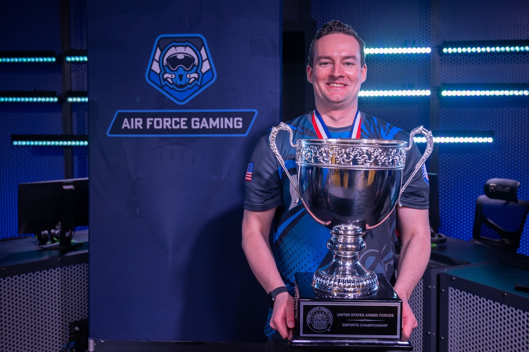 U.S. Air Force Major Chad Speer, from Wasilla, Alaska, poses with a championship trophy after winning the 2026 Armed Forces Esports Championship at Localhost in Philadelphia Pennsylvania, April 25, 2026. Service members competed in organized esports competition playing Marvel Rivals for championship honors while representing their respective services. Armed Forces Sports brings together service members from the Army, Marine Corps, Navy, Coast Guard, Air Force, and Space Force to compete at the national level. Armed Forces Sports promotes physical fitness, cognitive readiness, teamwork, and competitive opportunities for military members while supporting recruitment and retention efforts and strengthening partnerships through emerging sports platforms. (DoW photo by U.S. Navy Mass Communication Specialist 2nd Class Christopher Suarez)
