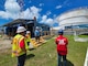 A person is talking to three other people as they come down a small set of stairs at a large fuel depot.