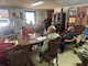 A group of individual sit around a large wooden conference room table.
