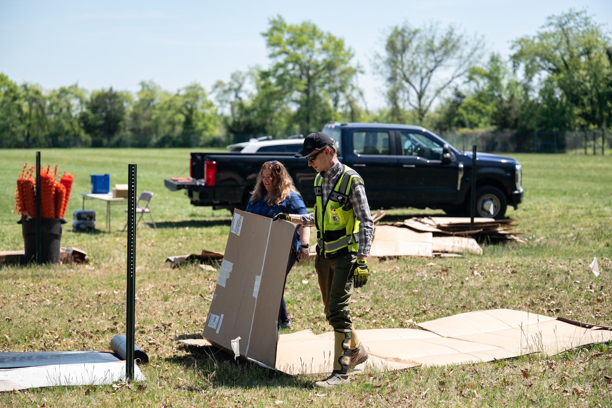 Team Dover Airmen are laying the groundwork for a future pollinator garden by covering an area on base with cardboard and weed-barrier fabric to prevent unwanted growth before planting begins. This process helps eliminate plant competition, allowing pollinator-friendly plants the best chance to thrive.