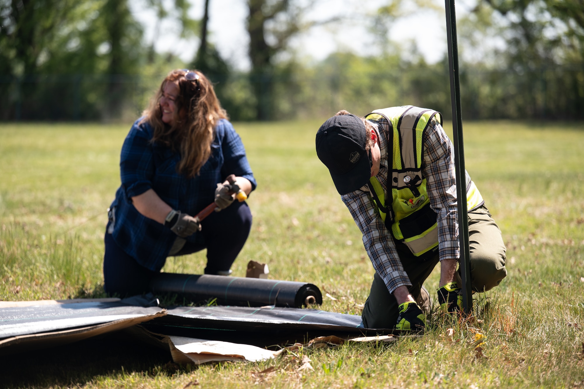 Team Dover Airmen are laying the groundwork for a future pollinator garden by covering an area on base with cardboard and weed-barrier fabric to prevent unwanted growth before planting begins. This process helps eliminate plant competition, allowing pollinator-friendly plants the best chance to thrive.