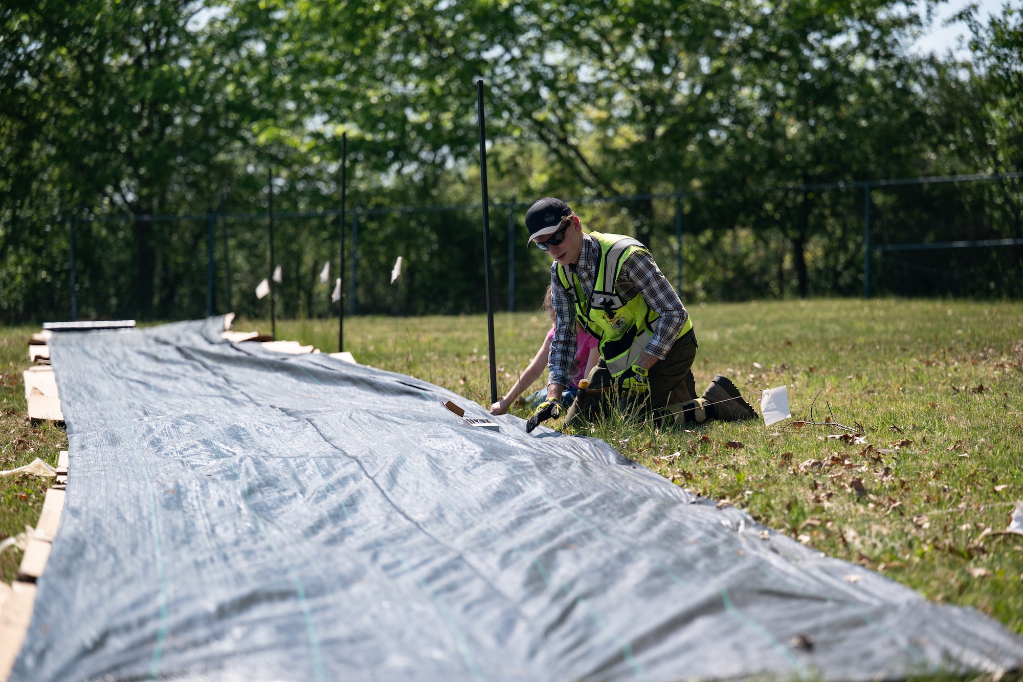Team Dover Airmen are laying the groundwork for a future pollinator garden by covering an area on base with cardboard and weed-barrier fabric to prevent unwanted growth before planting begins. This process helps eliminate plant competition, allowing pollinator-friendly plants the best chance to thrive.