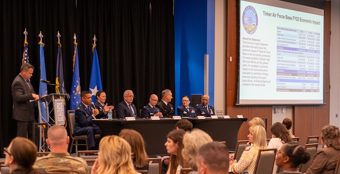 Military members sitting on panel with audience looking on.