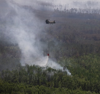 A CH-47 Chinook helicopter crew with B Company, 1st General Support Aviation Battalion, 169th Aviation Regiment, 78th Aviation Troop Command, Georgia Army National Guard, dumps water using a helicopter bucket during wildfire suppression efforts in Pineland, Georgia, April 25, 2026.