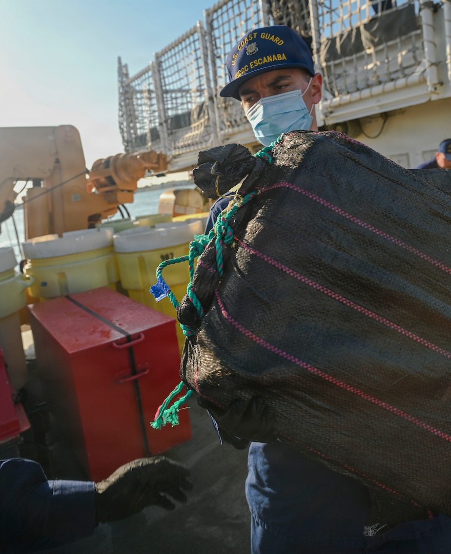 A crew member aboard USCGC Escanaba (907) carries a bale of cocaine during a drug offload of 7,050 pounds of narcotics at Port Everglades, Florida, April 27, 2026. The seized contraband was the result of one interdiction in the Caribbean Sea and one interdiction in the Eastern Pacific Ocean worth an estimated $53 million dollars. (U.S. Coast Guard photo by Petty Officer 2rd Class Eric Rodriguez)
