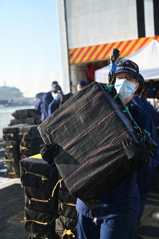 A crew member aboard USCGC Escanaba (907) carries a bale of cocaine during a drug offload of 7,050 pounds of narcotics at Port Everglades, Florida, April 27, 2026. The seized contraband was the result of one interdiction in the Caribbean Sea and one interdiction in the Eastern Pacific Ocean worth an estimated $53 million dollars. (U.S. Coast Guard photo by Petty Officer 2nd Class Eric Rodriguez)