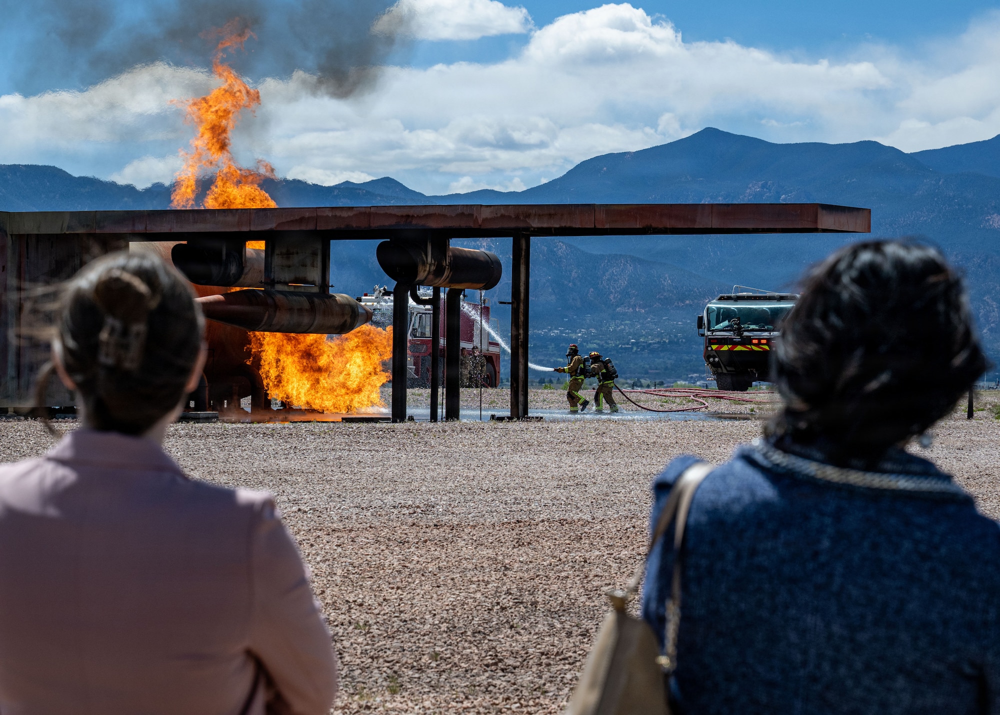Members of a tour group watch firefighters put out a training fire.