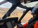 A U.S. Coast Guard pilot from Coast Guard Air Station Kodiak looks out from an MH-60 Jayhawk helicopter at two rescued hikers and a aviation survival technician in Unalaska, Alaska, March 27, 2026. The aircrew evacuated the hikers from Makushin Volcano on Unalaska Island after one of them sustained a leg injury, transporting them to emergency medical services. (U.S. Coast Guard by Lt. Cmdr. Joshua Womboldt )