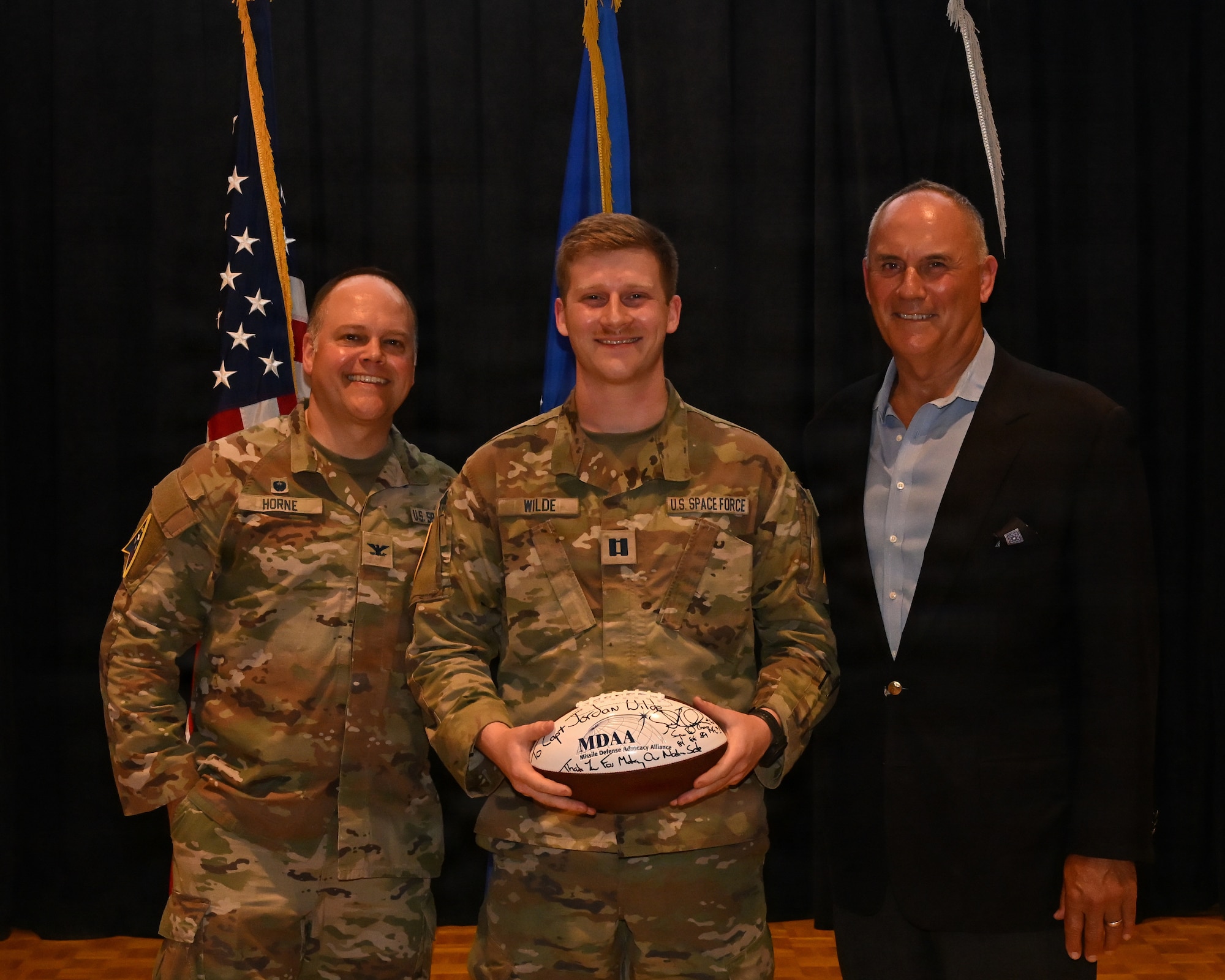 Three people stand on stage and pose for a photo