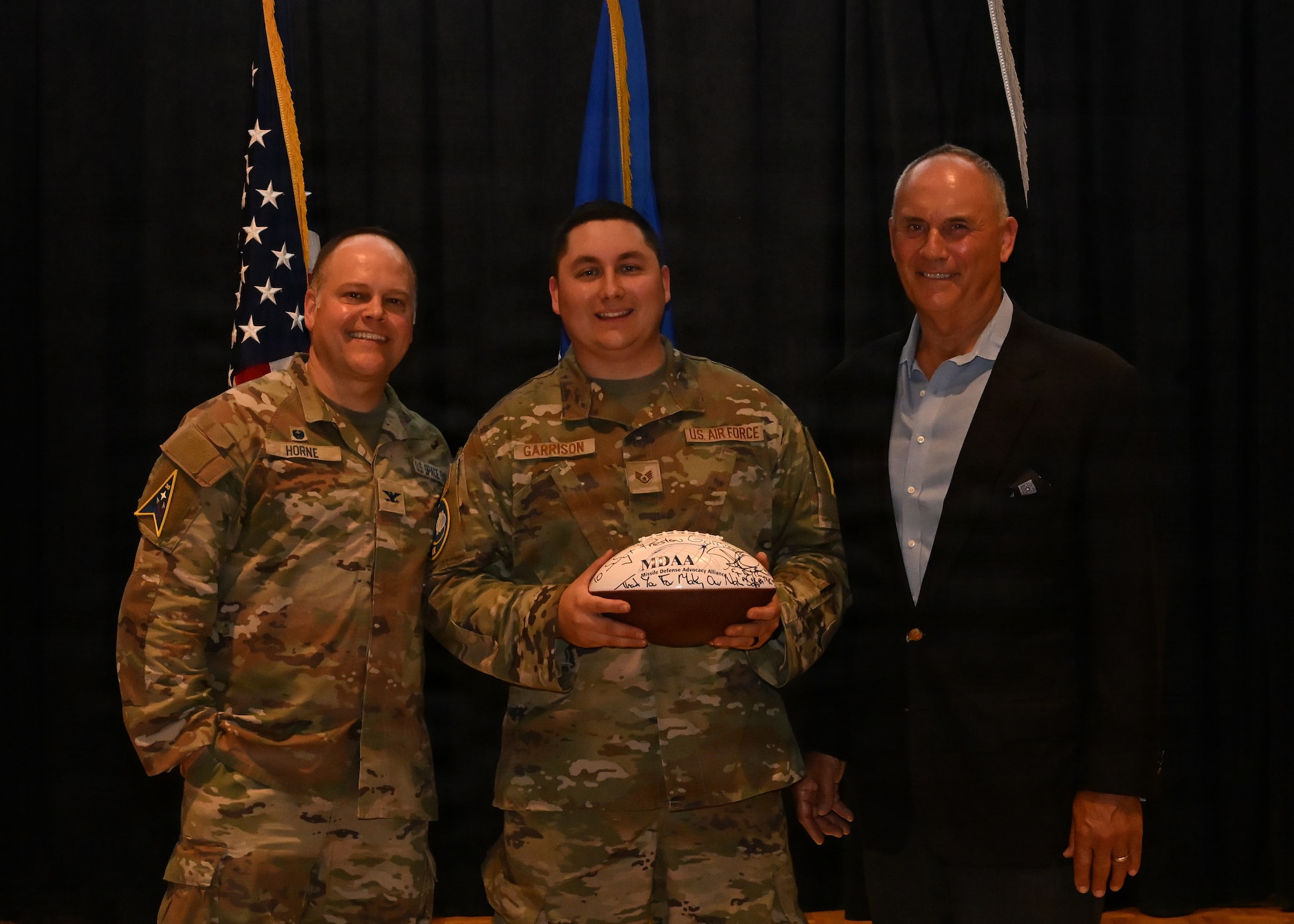 Three people stand on stage and pose for a photo