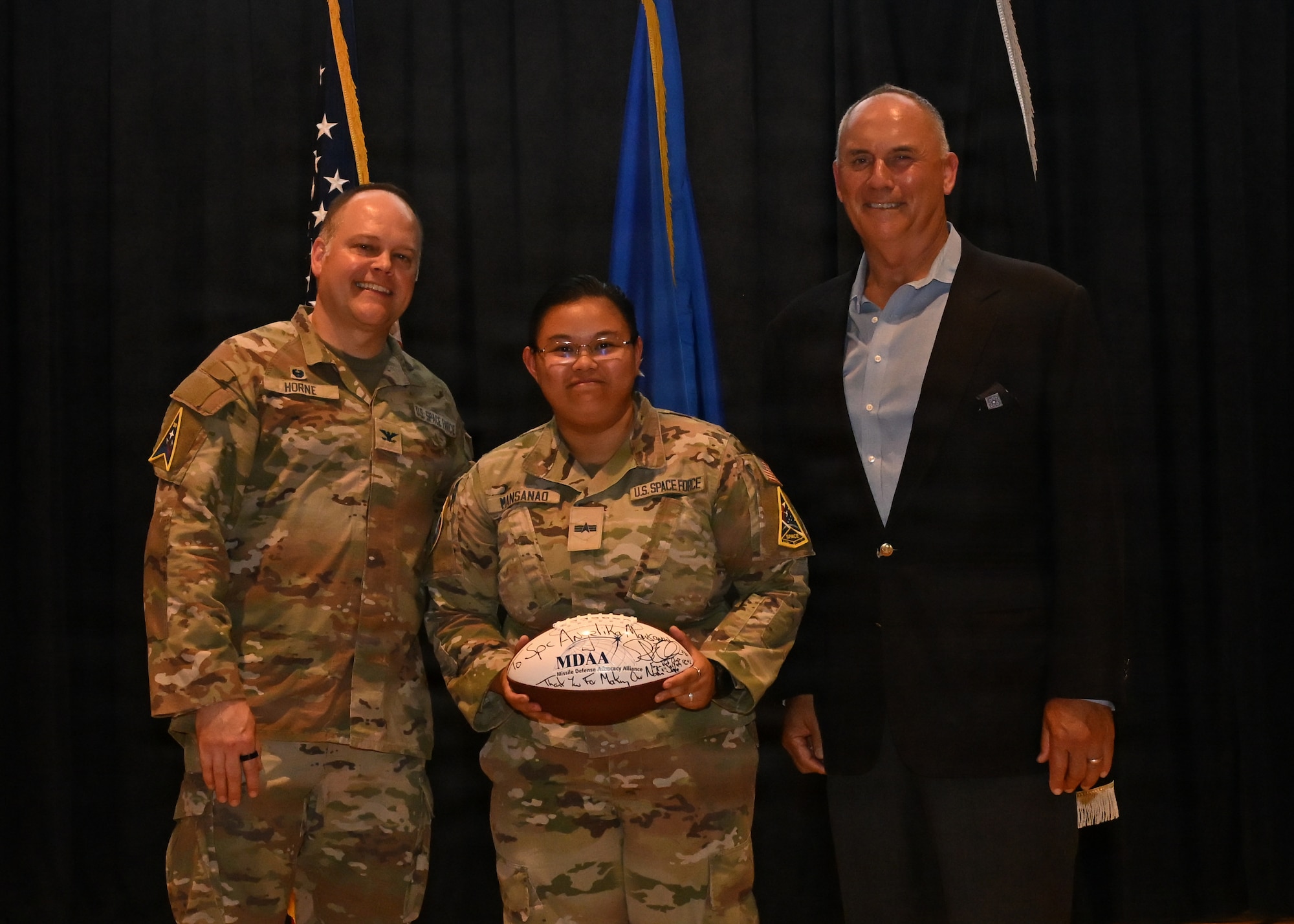 Three people stand on stage and pose for a photo