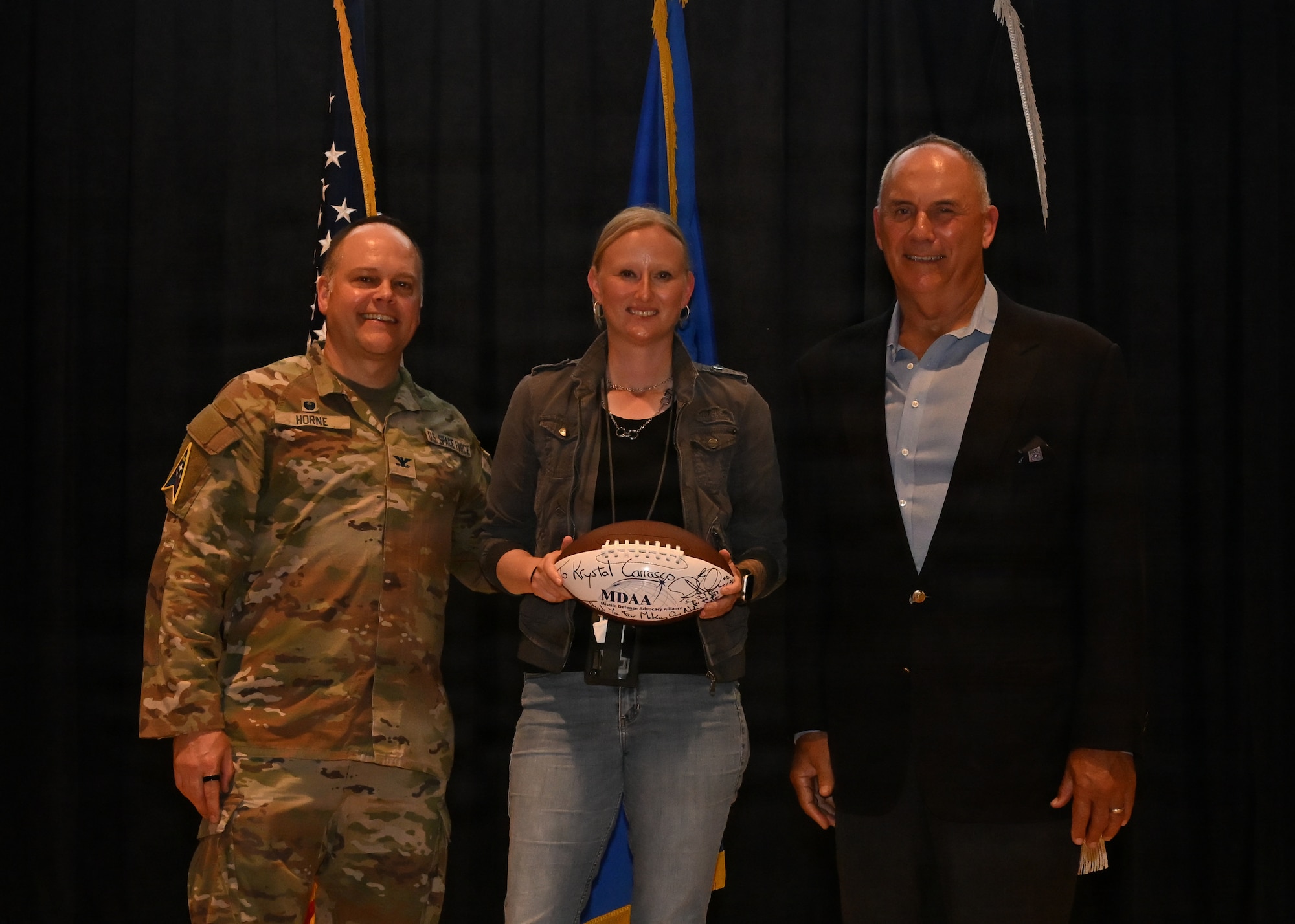 Three people stand together on stage and pose for a photo