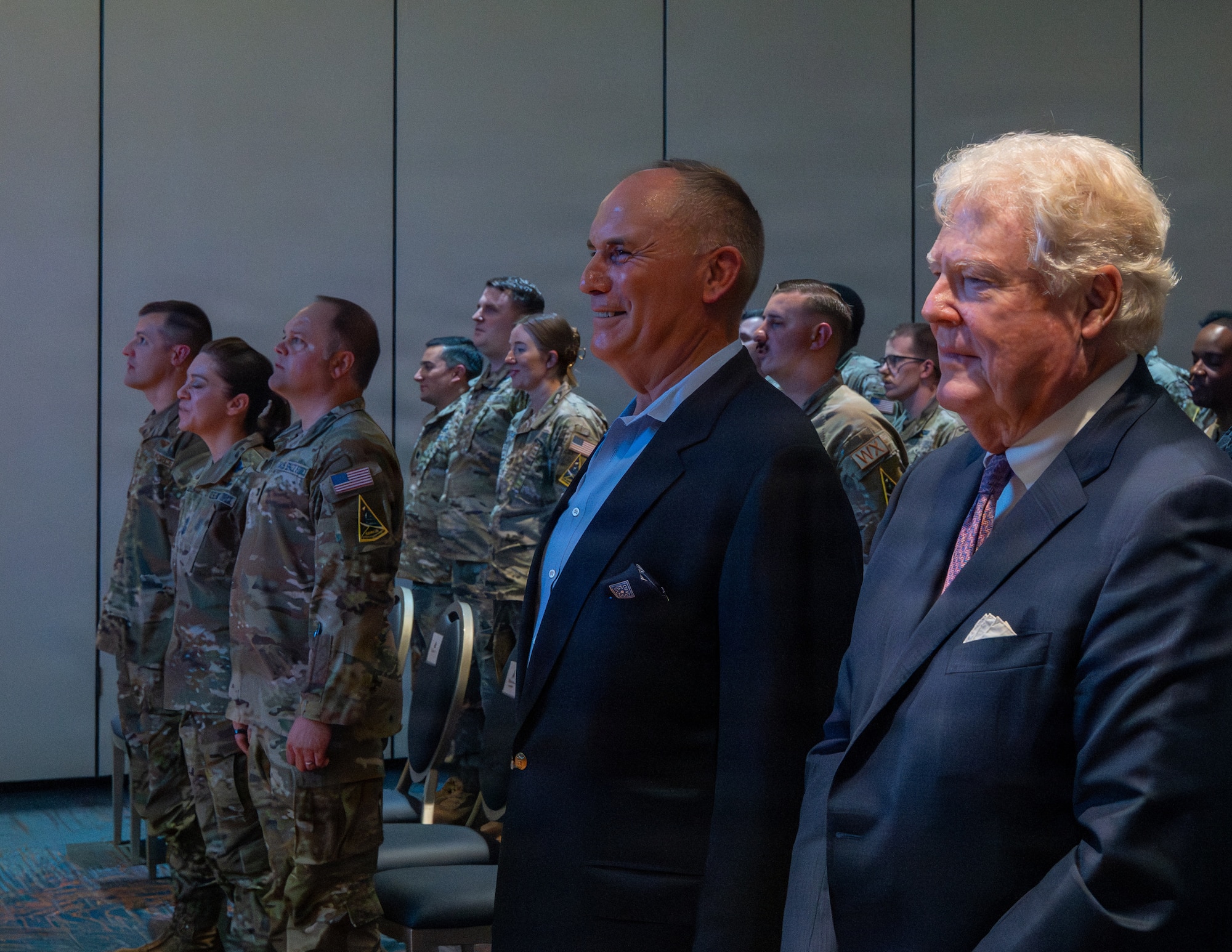 People stand up in front of their chairs.